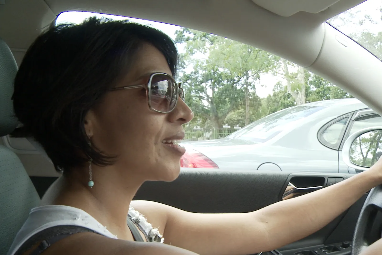 Carmen driving, sunglasses catching the light